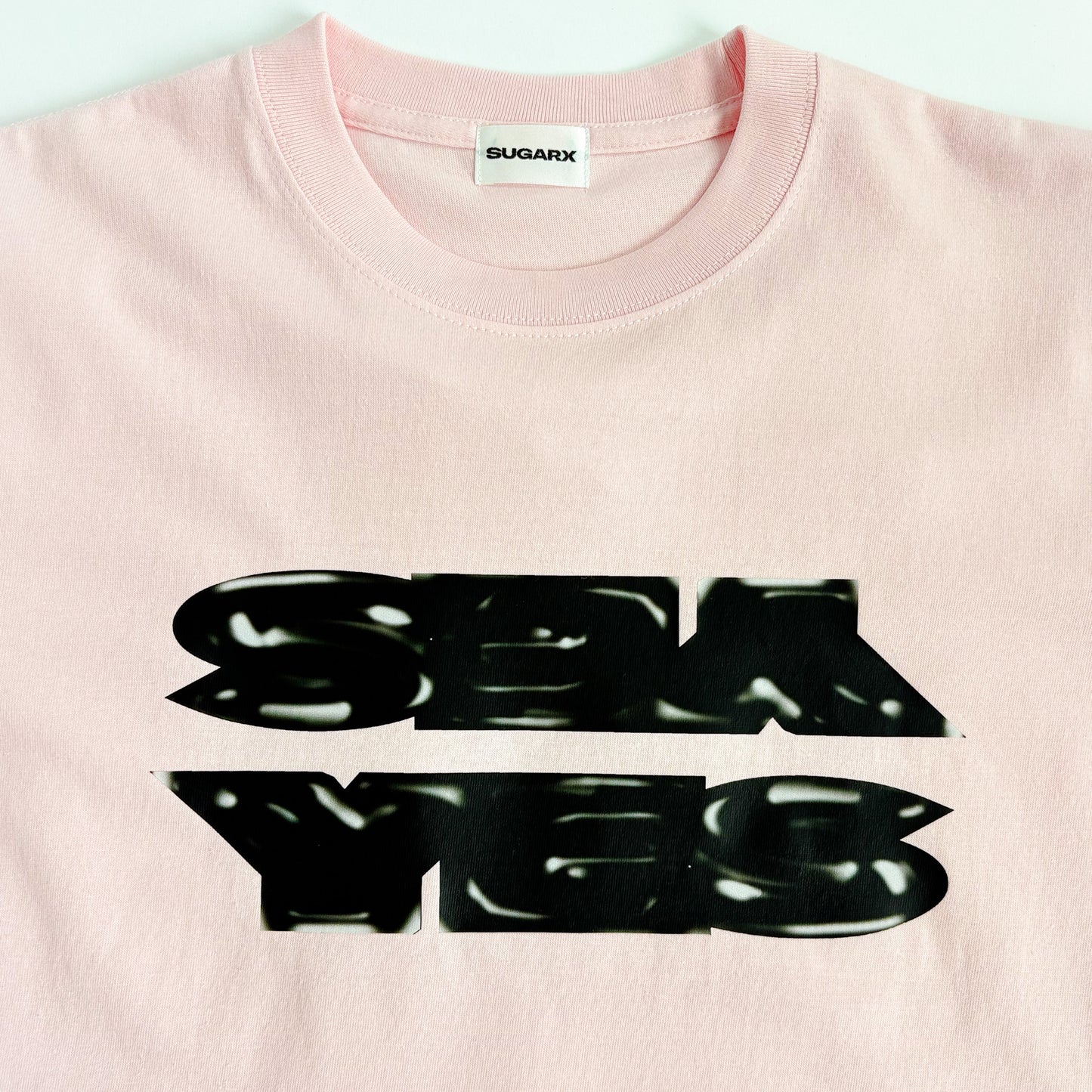ピンクのクルーネックTシャツ、フロントに黒の大判プリント