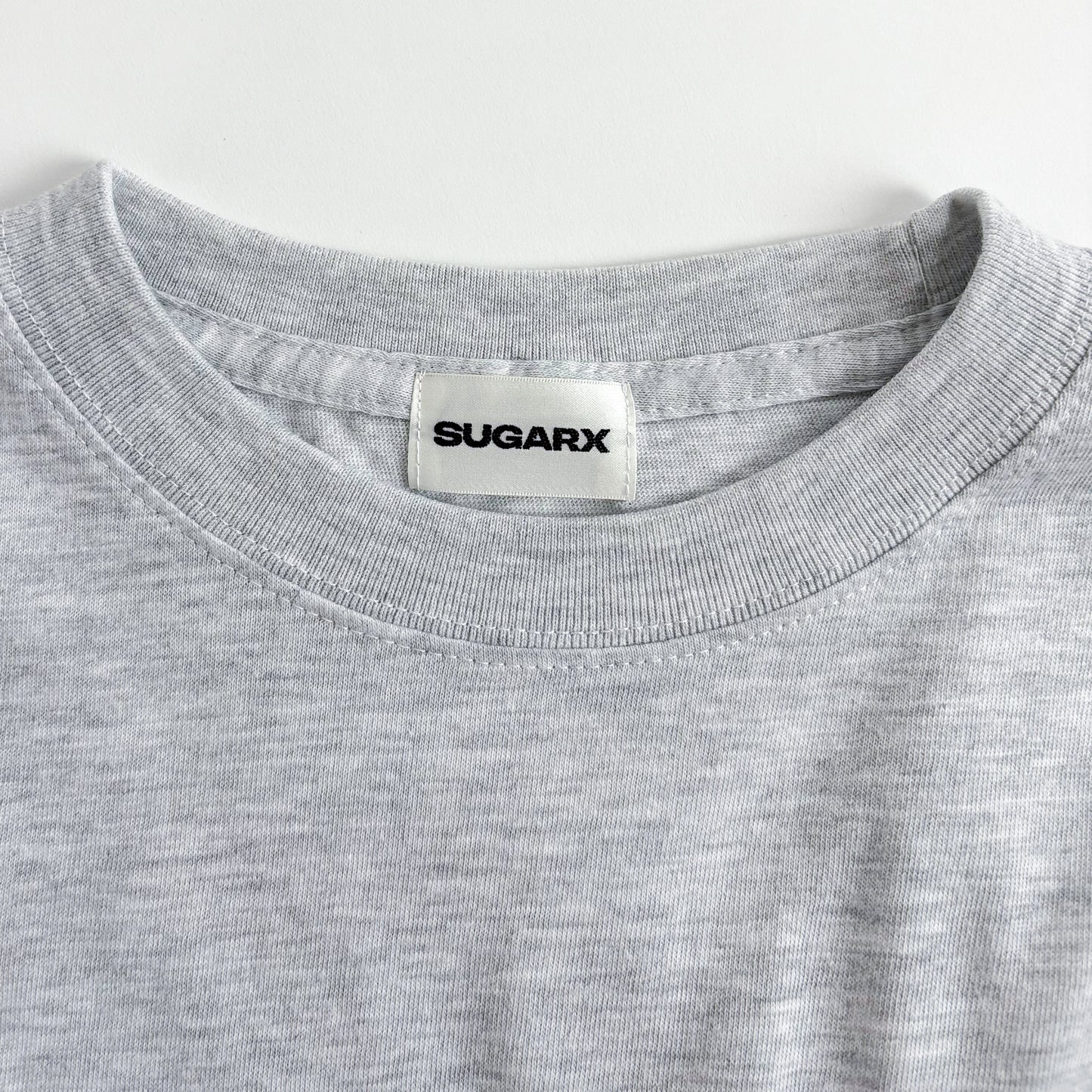 グレー長袖Tシャツ、首元はクルーネックでブランドタグ付き