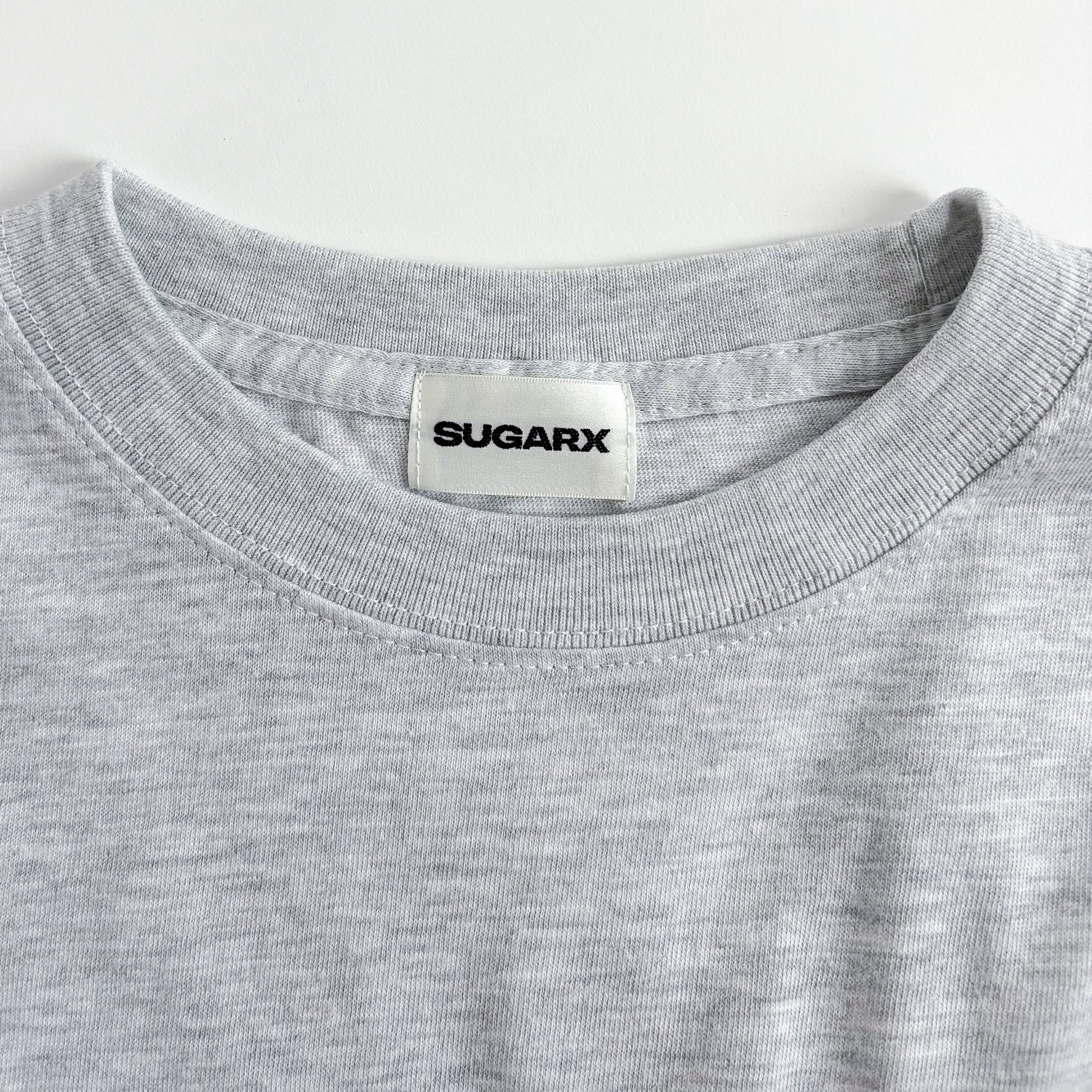 グレー長袖Tシャツ、首元はクルーネックでブランドタグ付き