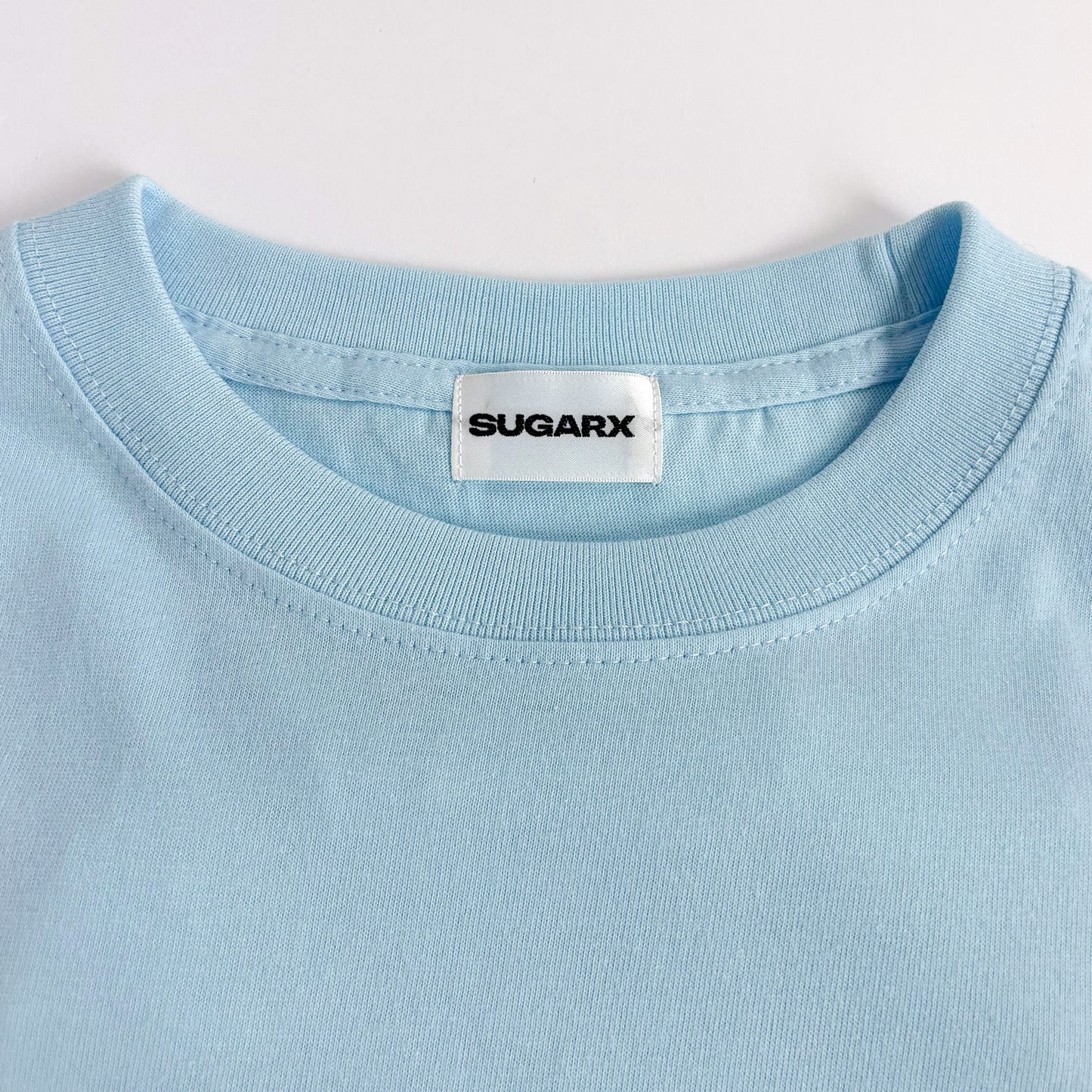 サックスブルー長袖Tシャツのクルーネック、SUGARXタグ付き