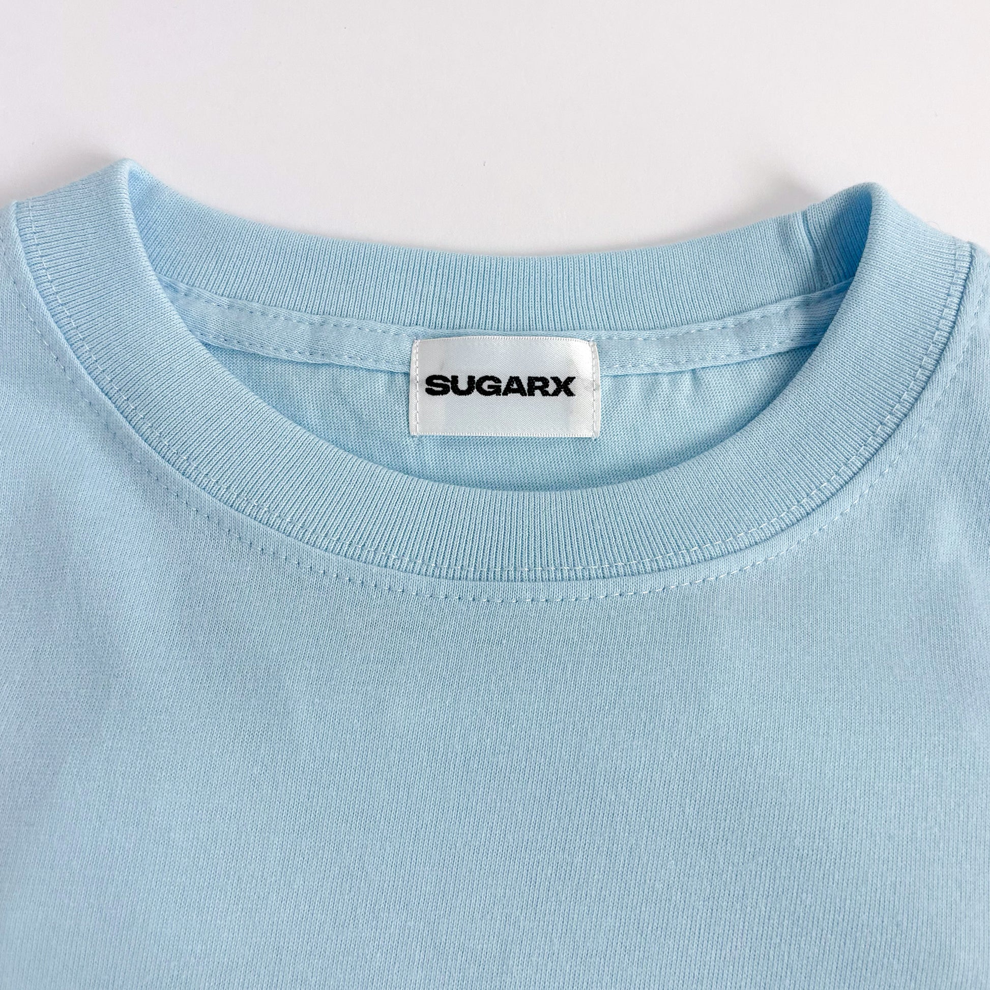 サックスブルー長袖Tシャツのクルーネック、SUGARXタグ付き